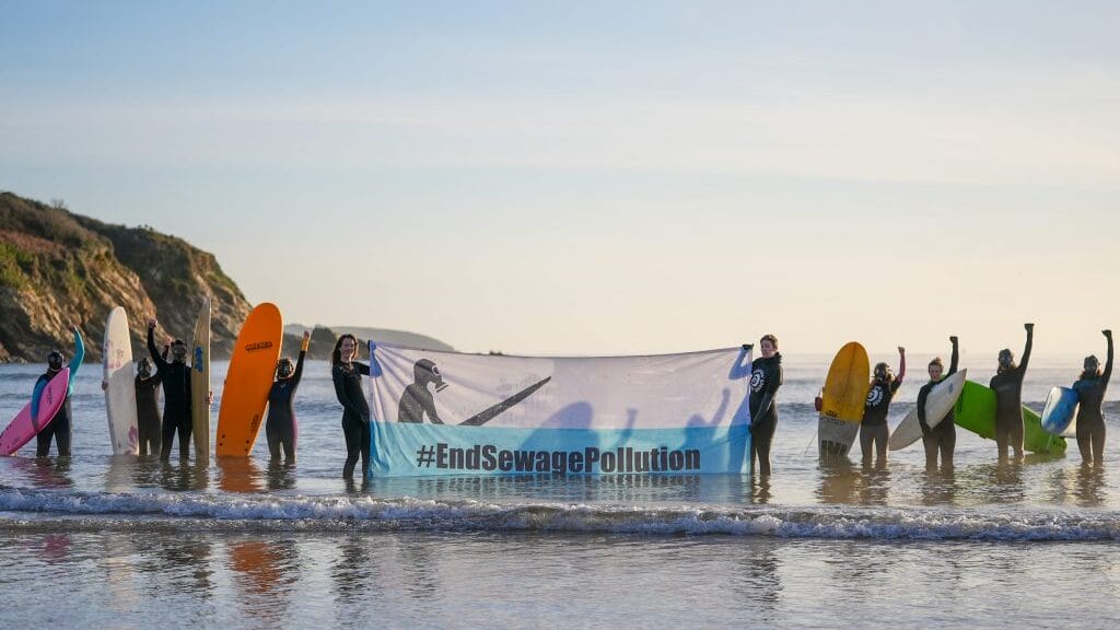 Anti sewage campaigners hold a banner in the waves.