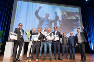 Group of award winners standing on a stage celebrating their success.