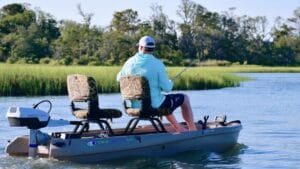 Man fishing in fresh water from a small, two-seater boat that has ePropulsion electric outboard motor.