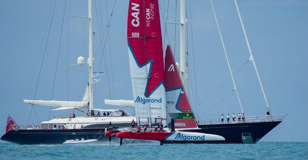 Canada SailGP team foiling whilst sailing past superyacht