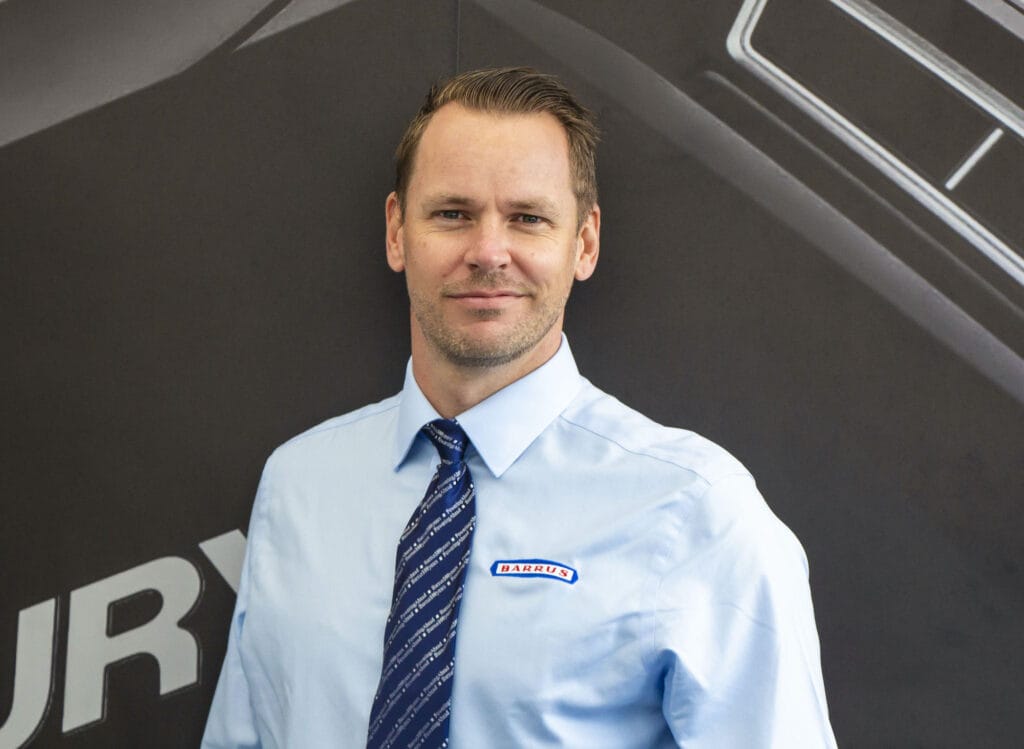 Head and upper body shot of man dressed in shirt with Barrus company logo and tie.