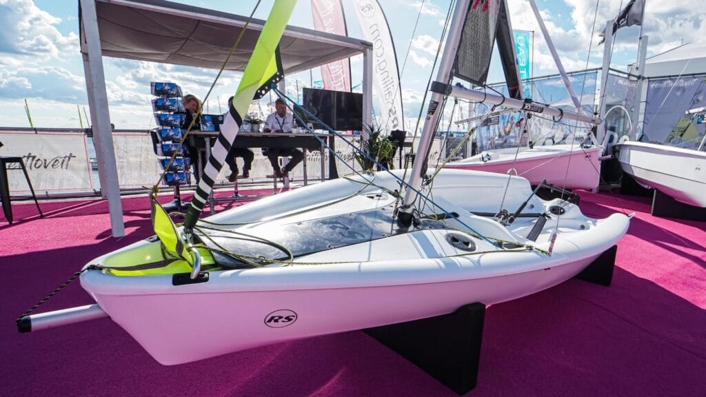 Side view of a sailing dinghy on a stand at a boat show.