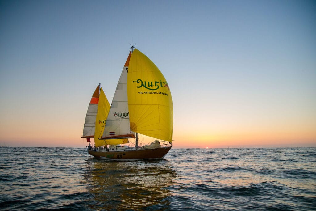 Yacht sailing in ocean with full sails hoisted.