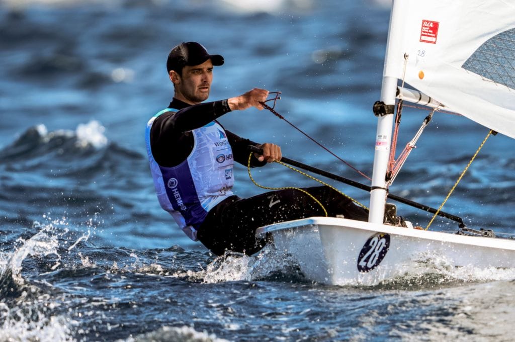 Sailor with baseball cap on sailing a single handed dinghy