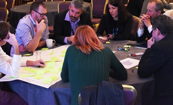 Group of adults around a table bringing together ideas.