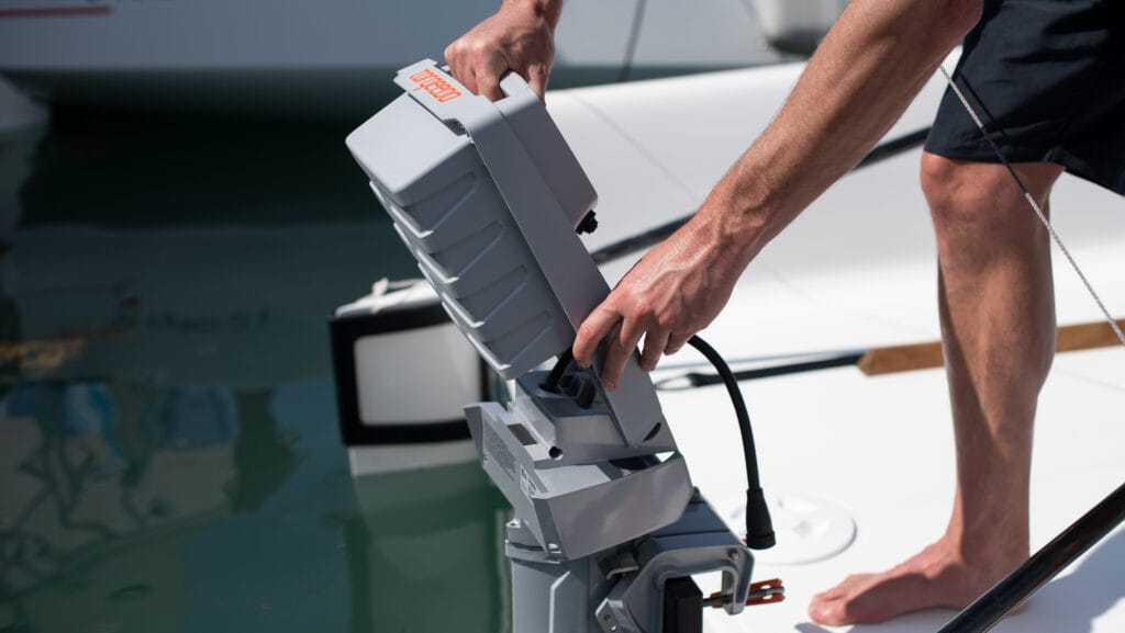 barefooted man attaching battery of electric outboard on the back of boat