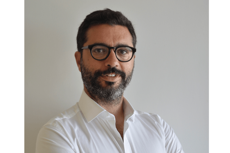 Head and shoulders shot of a bearded man wearing glasses looking at the camera.