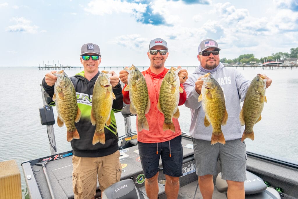 three men with sunglasses and fish in their hands