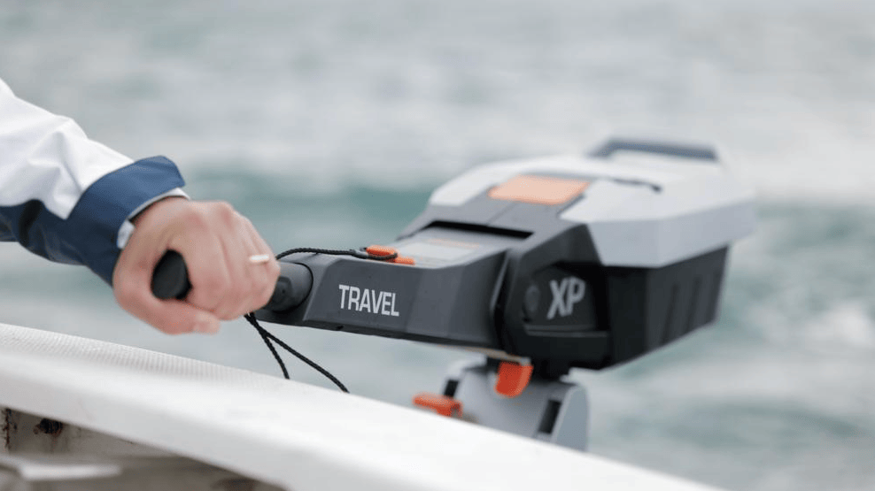 Hand steering a Torqeedo electric outboard tiller at the back of a boat