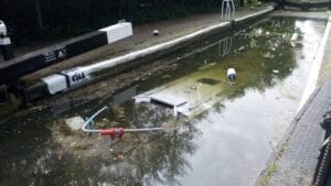 A narrow boat submerged in a canal lock full of water.