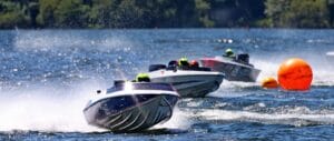 three racing boats bounce along the water after rounding an orange buoy