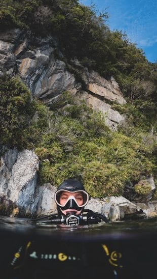 scientist's head pokes out of water, in diving gear