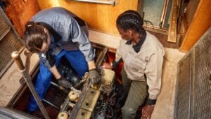 Top view of two people repairing boat engine in pit, copy space