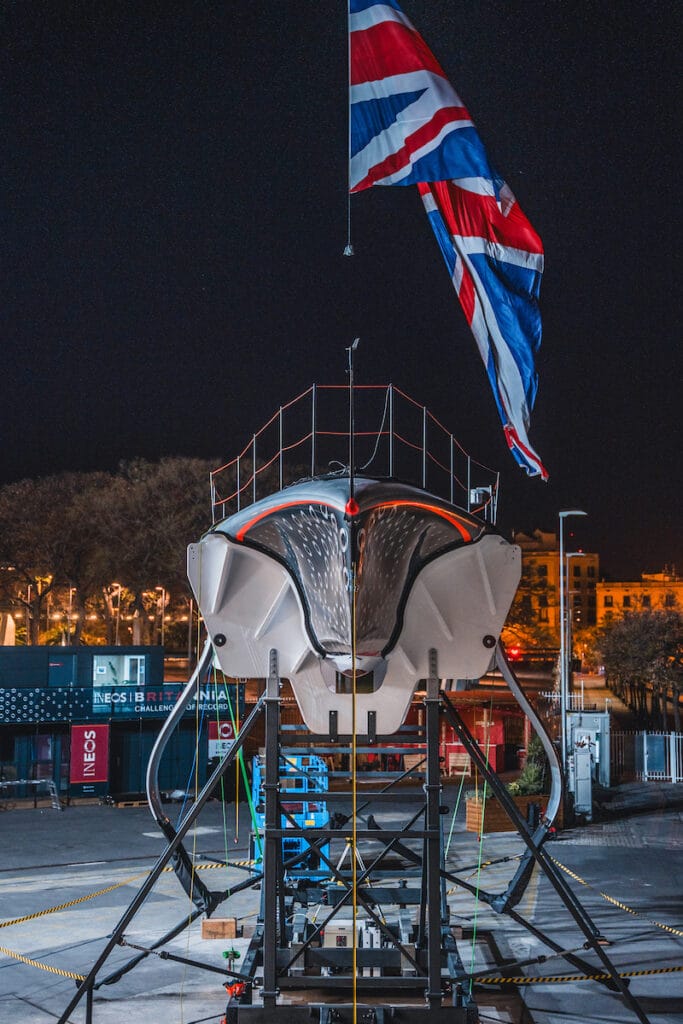 Bow on picture of INEOS Brittania foiling race boat at night on hardstanding