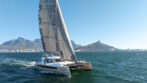 A Balance Catamaran sails across a blue sea with mountains in the background