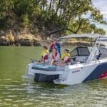 two kids and two adults, family fishing on small power boat