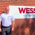 a man stands by a Wessex Resins sign