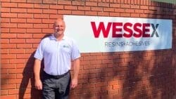 a man stands by a Wessex Resins sign