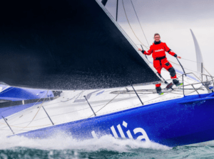 Pip Hare stands proudly on her IMOCA which she hopes to fund in the Vendée Globe