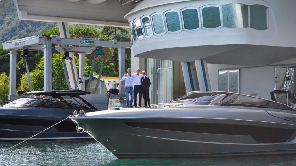 Three men standing on bow of luxury silver powerboat