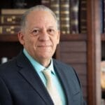 Louis Diaz looks at the camera. He stands in front of a bookcase