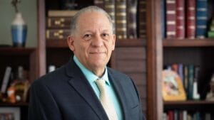 Louis Diaz looks at the camera. He stands in front of a bookcase