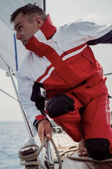 A sailor in red and white apparel adjusts the boat