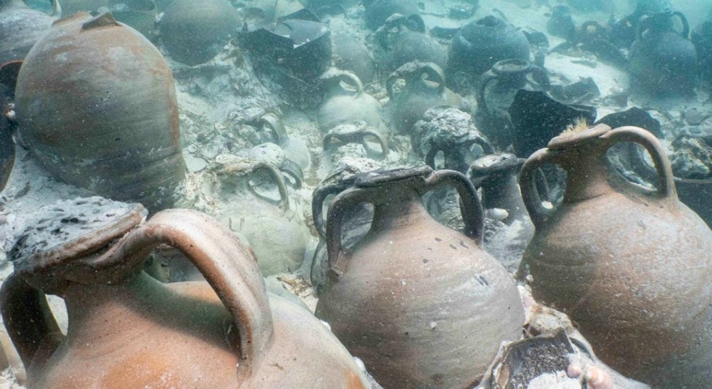 treasure from wreck found in Mallorca. Earthenware containers appear neatly lined up in the sand