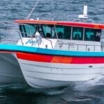 bow on shot of white hulled workboat with red stripe