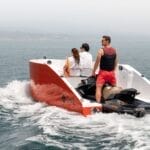 jet ski coupled to boat hull to make jet ski boat with two people sat in bow