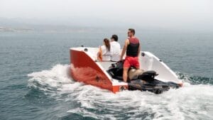 jet ski coupled to boat hull to make jet ski boat with two people sat in bow