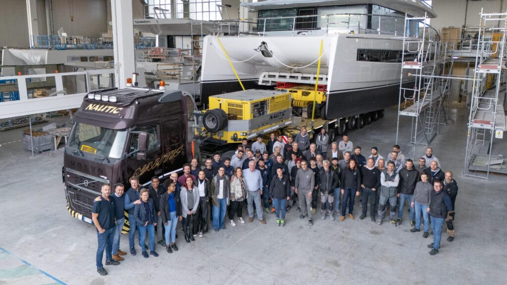 group of shipyard workers in front of boat on truck