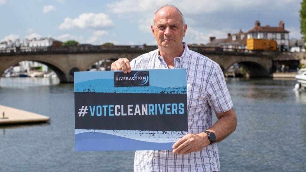Chap holds up sign encouraging people to vote for clean rivers after River Thames has dangerously high levels of E-coli prior to Henley Royal Regatta