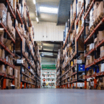 Inside a warehouse. Multiple shelves stocked with goods from VDM-Reya, Henri-Lloyd French distributor