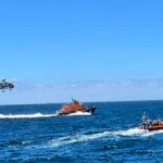 helicopter follows two RNLI rescue craft