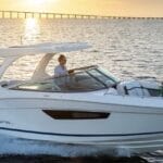 white speedboat with woman at bow and sunset background