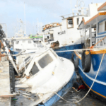 Fishermen try to move boats which have been crushed against dock in Hurricane Beryl