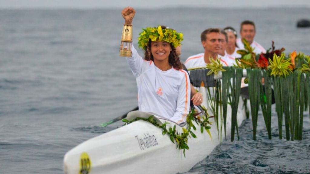 People in boat hold Olympic torch aloft