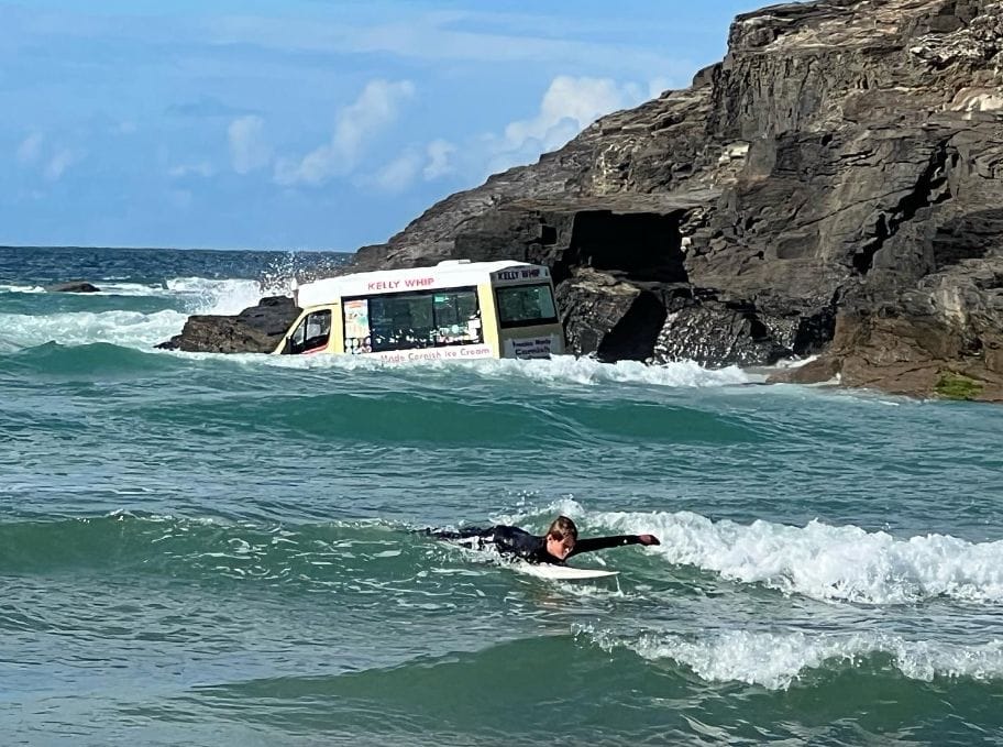 surfer swims past ice cream van swept out to sea in Cornwall