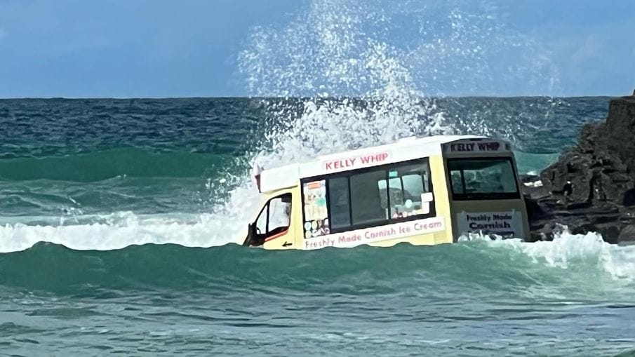 ice cream van swept out to sea with waves crashing over it in Cornwall