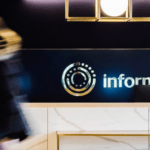 Woman walks by a desk with Informa logo in background