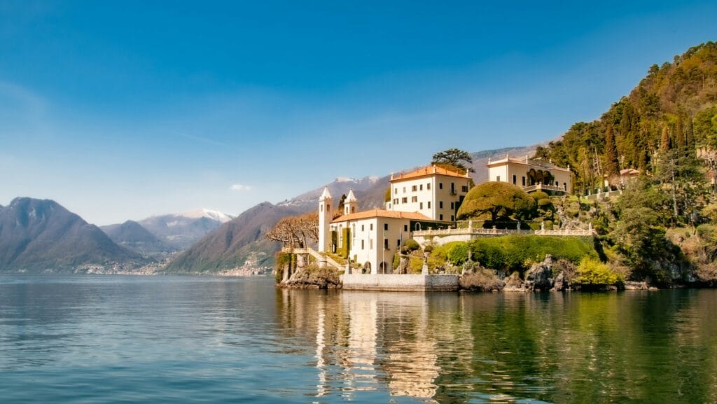View of Lake Como with buildings and mountains in the background. Site of tragic drowning of British tourist after diving into water and boat drifting off