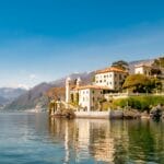 View of Lake Como with buildings and mountains in the background. Site of tragic drowning of British tourist after diving into water and boat drifting off