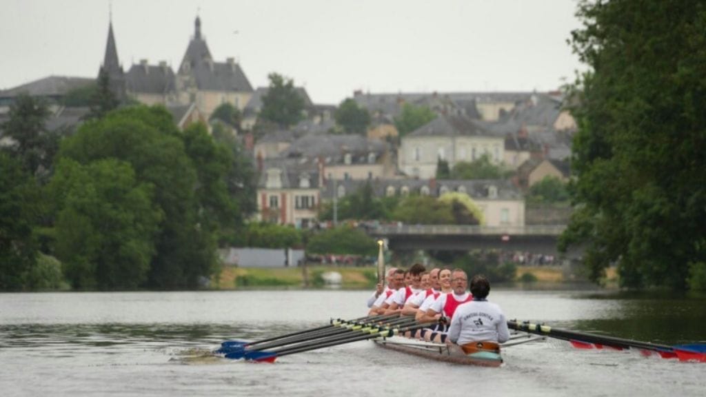 Rowers on river with Olympic flame