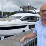 Robert Parton British Marine president looks at camera. He's standing i front of a boat while he considers marine strategy for UK with new government being formed