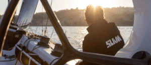 Back of sailor's head who is gazing at sunset while wearing SLAM sailing clothes