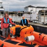 Adventurer Ed Pratt standing on Gravesend's Atlantic 85 with RNLI Commander Karla.