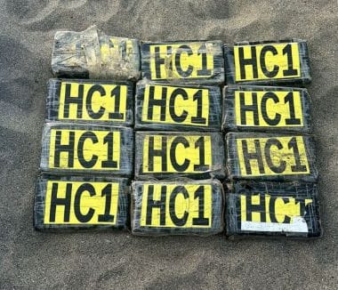 Packets of drugs - thought to be cocaine or heroin - stacked on sand after boat found with 14 deceased