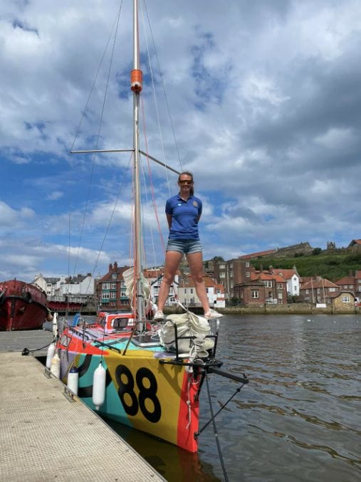 Sailor stands on mini boat which she will sail solo around world