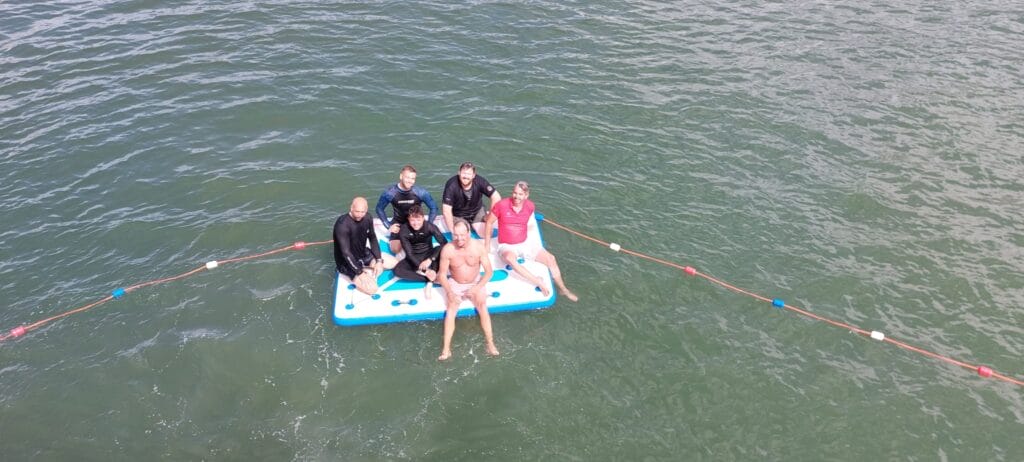 group of people smiling on square swim platform in the sea